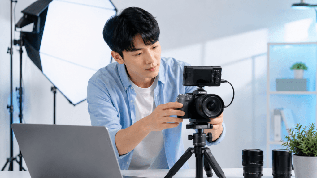Creator Tips | Content, Photography, Video & Workflow 7 Creator adjusting a camera on a tripod in a bright studio setup with softbox lighting and laptop nearby